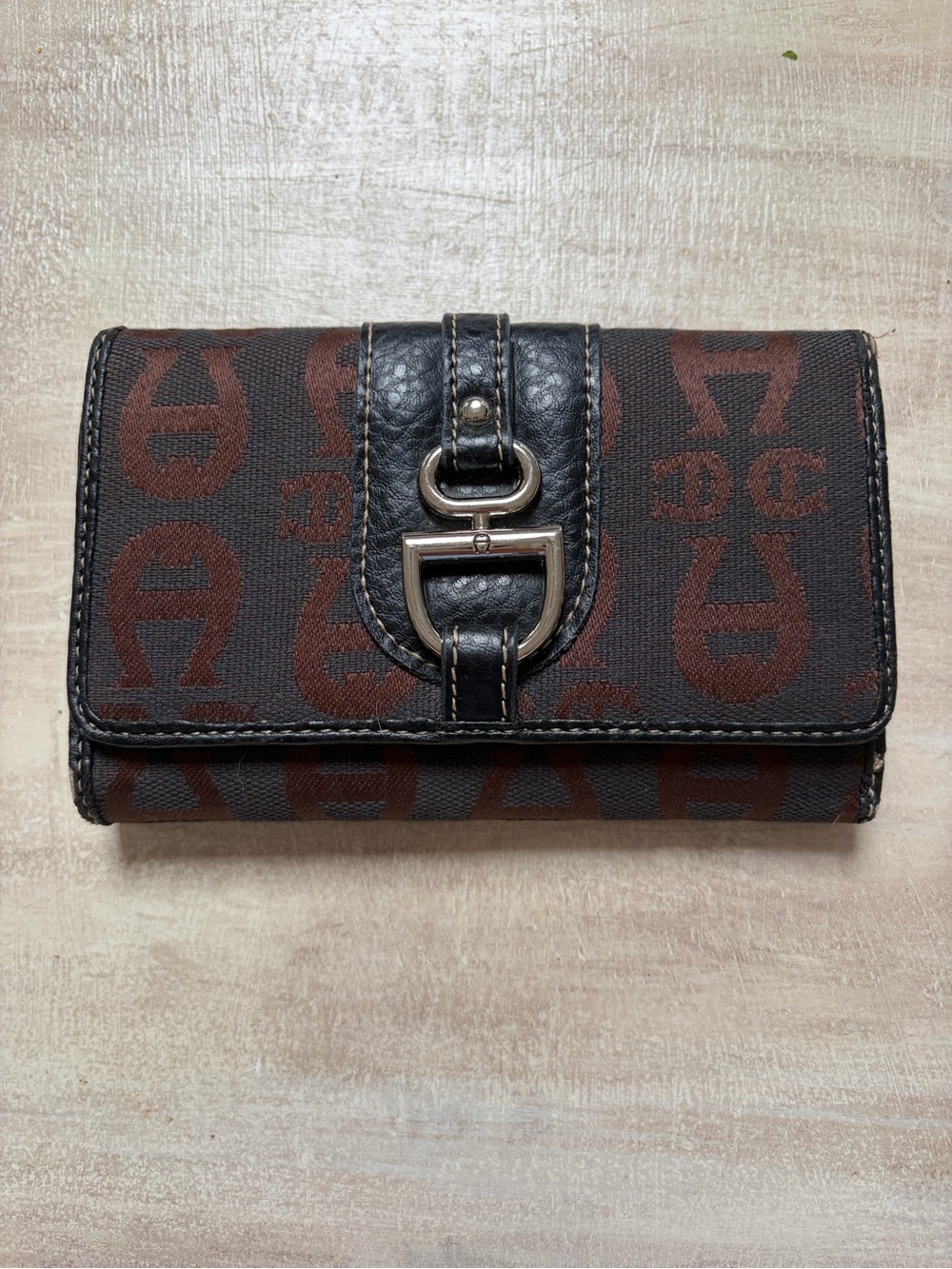 Etienne Aigner signature logo tri-fold wallet with a black strap and silver-tone